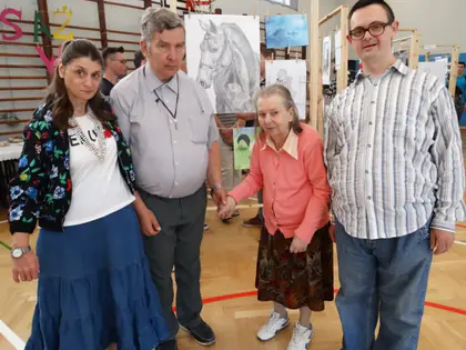 Mieszkańcy z opiekunami na wernisażu prac uczniów w sali gimnastycznej