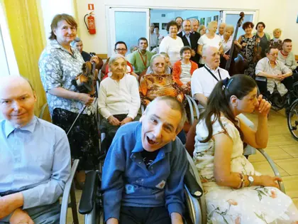 Mieszkańcy z psem przewodnikiem słuchają koncertu orkiestry kameralnej