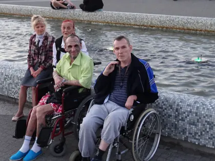 Mieszkańcy na wózkach przy brzegu fontanny w Multimedialnym Parku Fontann