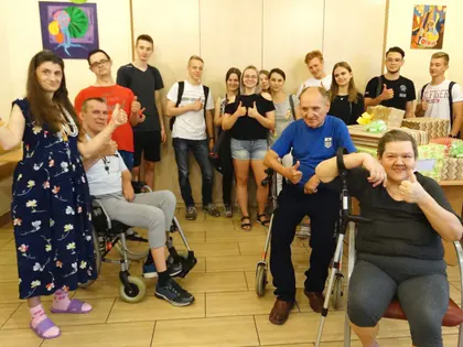 Uczniowie technikum i mieszkańcy z uniesionymi kciukami w świetlicy