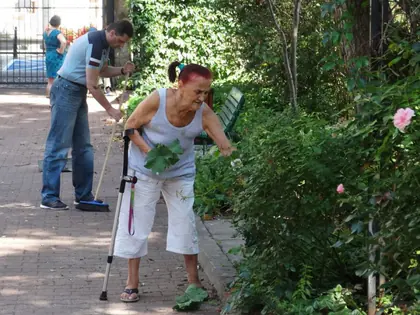 Mieszkanka o kulach i opiekun pielęgnują rośliny w ogrodzie sensorycznym