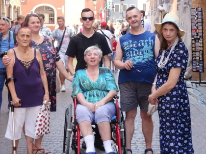 Mieszkańcy z opiekunami na ulicy Starego Miasta podczas letniego spaceru