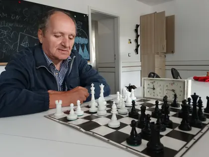 Mieszkaniec gra w szachy, obok zegar szachowy