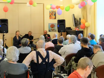 Muzycy grają koncert dla mieszkańców w świetlicy ozdobionej balonami