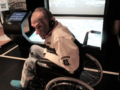 Mieszkaniec na wózku ogląda multimedialną ekspozycję w muzeum
