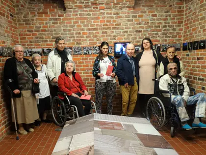 Mieszkańcy z opiekunami w ceglanej sali Muzeum Warszawskiej Pragi