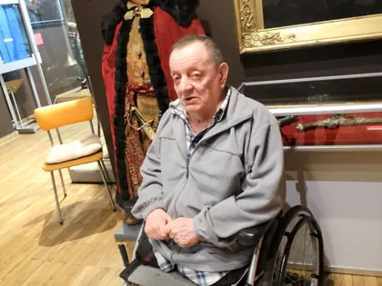 Mieszkaniec na wózku obok figury szlachcica w czerwonym płaszczu