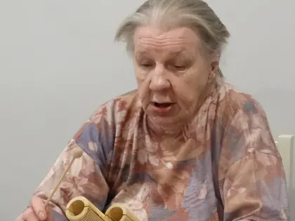 Starsza mieszkanka gra na drewnianym instrumencie podczas warsztatów