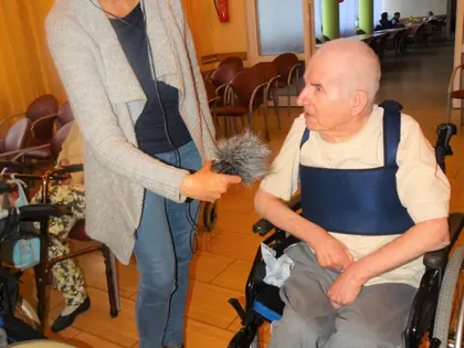 Kobieta ze słuchawkami nagrywa wypowiedź mieszkańca na wózku
