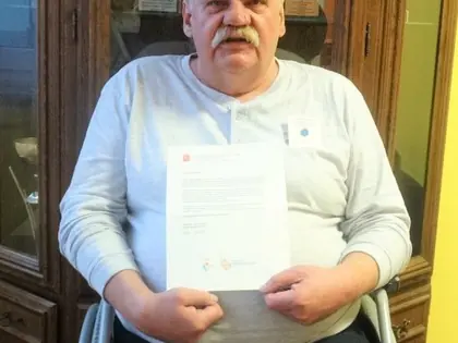 Mieszkaniec na wózku trzyma list z podziękowaniem od Prezydent Warszawy