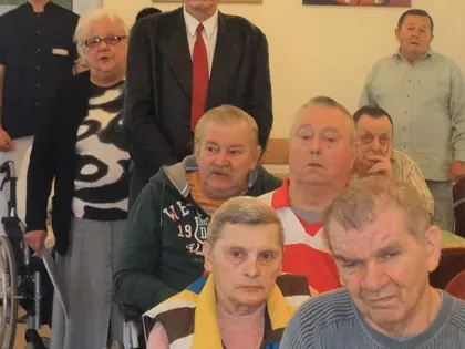 Mieszkańcy i opiekunowie pozują w świetlicy podczas obchodów
