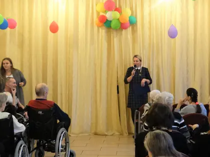 Prowadząca z mikrofonem zapowiada koncert w świetlicy z balonami