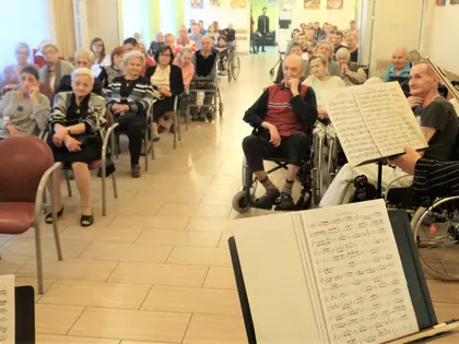 Mieszkańcy słuchają koncertu muzyki dawnej, na pierwszym planie pulpit z nutami