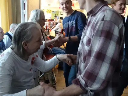 Młody mężczyzna w kraciastej koszuli tańczy z mieszkanką, trzymając ją za ręce