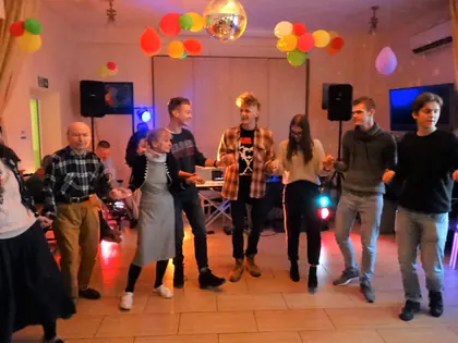 Mieszkańcy i młodzież tańczą w świetlicy oświetlonej kolorowymi światłami dyskoteki