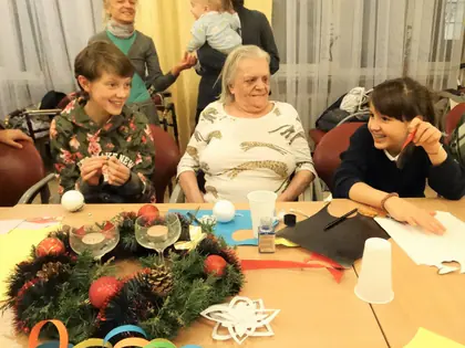 Mieszkanki i dziewczęta przy stole ze stroikiem i papierowymi gwiazdkami