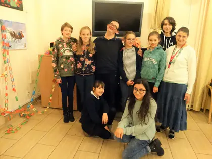 Młodzież i mieszkanki pozują przy długim papierowym łańcuchu