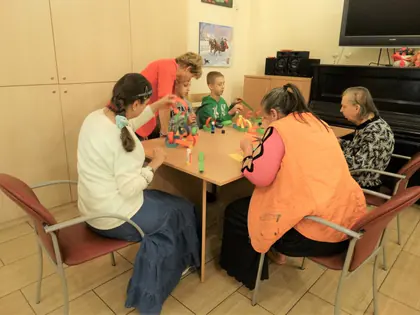 Młodzież i mieszkańcy tworzą ozdoby z muszelek i kolorowych elementów przy stole