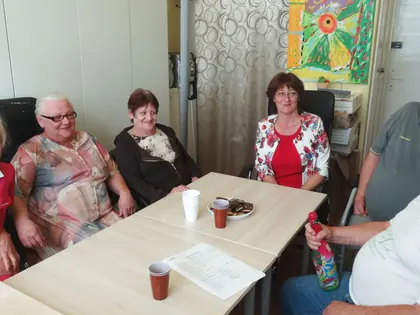 Seniorzy przy stole z kawą podczas spotkania przy projekcie