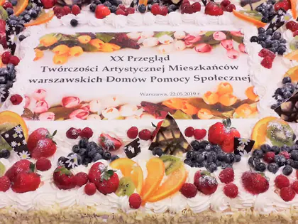 Duży tort z owocami i napisem XX Przegląd Twórczości Artystycznej Mieszkańców
