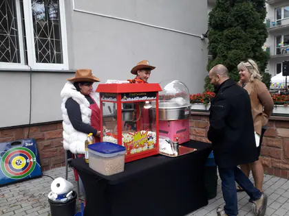 Stoisko z popcornem i watą cukrową obsługiwane przez osoby w kapeluszach