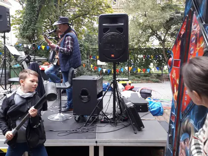 Chłopiec bawi się przed sceną, na której gra zespół w kapeluszach kowbojskich