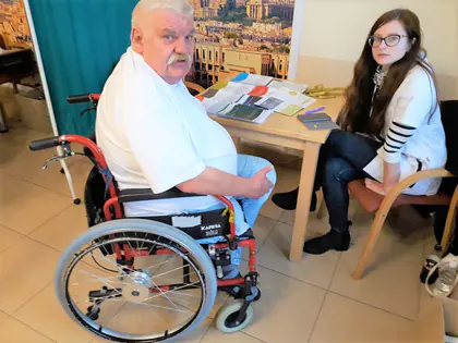 Mieszkaniec na wózku rozmawia z młodą kobietą przy stoliku