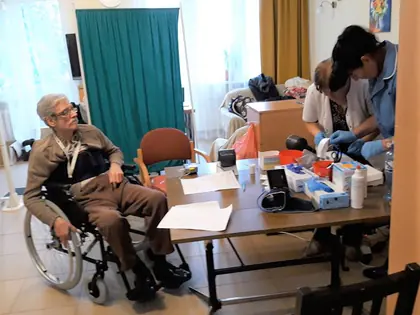 Mieszkaniec na wózku przy stoliku z ciśnieniomierzem podczas badań