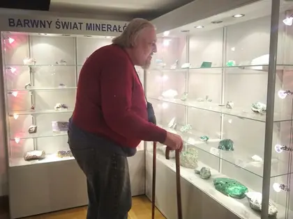 Mieszkaniec z laską ogląda gablotę z minerałami w muzeum