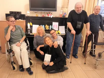 Mieszkańcy i aktorzy fundacji pozują przy pianinie po spotkaniu poetycko-teatralnym