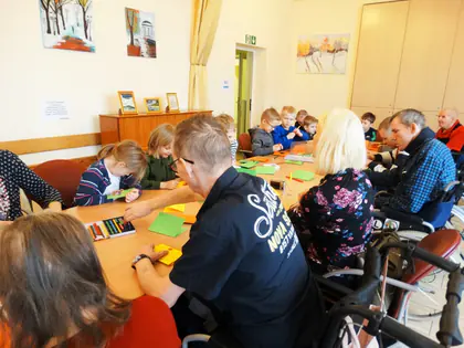 Przedszkolaki i mieszkańcy rysują przy wspólnym stole w świetlicy