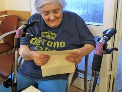 Mieszkanka czyta list siedząc przy balkoniku