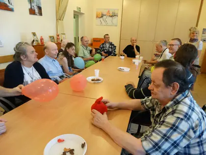 Mieszkańcy z balonami przy stole podczas zajęć