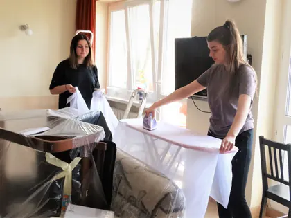 Dwie dziewczyny prasują białe zasłony w pokoju