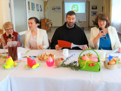 Prowadzące i zakonnik przy stole wielkanocnym z koszyczkiem