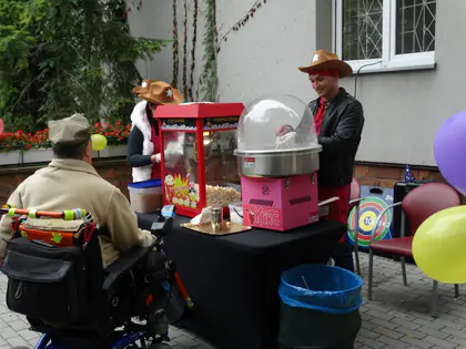 Mieszkaniec na wózku przy stoisku z popcornem i watą cukrową