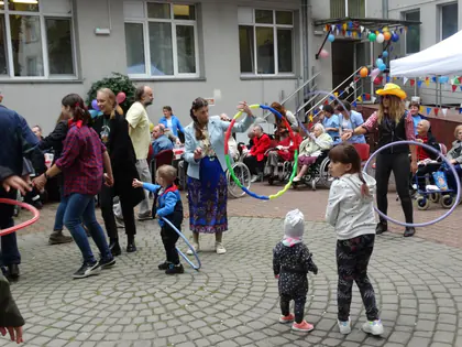 Dzieci i dorośli tańczą z obręczami hula-hoop na podwórku
