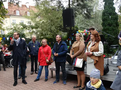 Organizatorzy i goście przy scenie, mężczyzna mówi do mikrofonu