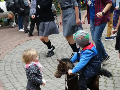 Dzieci na konikach na kółkach, obok tańczą harcerki