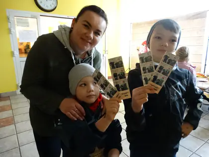 Kobieta i dwaj chłopcy pokazują paski zdjęć z fotobudki