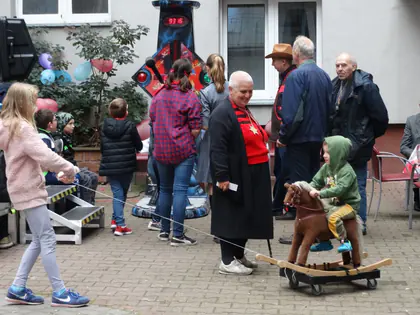 Goście pikniku przy automacie do mierzenia siły uderzenia, dziecko na koniku