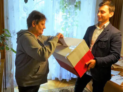 Mieszkanka w swetrze wrzuca kartę do urny w pokoju
