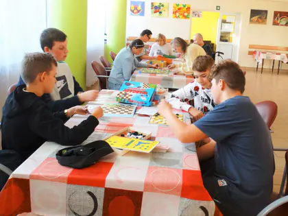 Młodzież i mieszkańcy grają w gry planszowe przy stołach w świetlicy