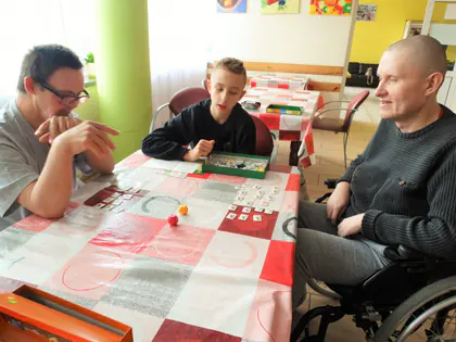 Mieszkańcy i chłopiec grają w grę przy stole