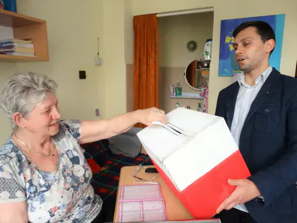 Mieszkanka wrzuca kartkę do urny podczas wyborów do Rady Mieszkańców