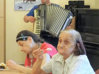 Akordeonista gra dla mieszkanek jedzących ciasto przy stole