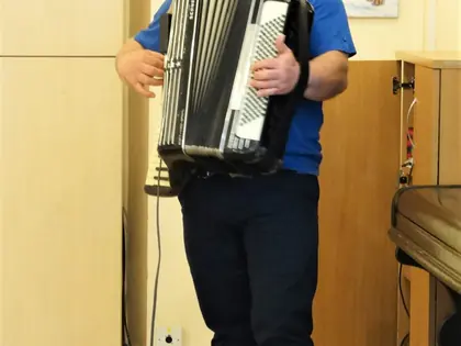 Akordeonista gra stojąc przy pianinie