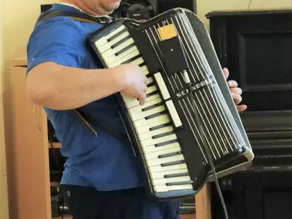 Akordeonista w niebieskiej koszulce gra w świetlicy