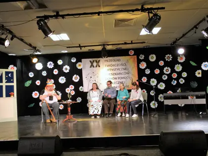 Scena przeglądu twórczości z aktorami siedzącymi przy stoliku