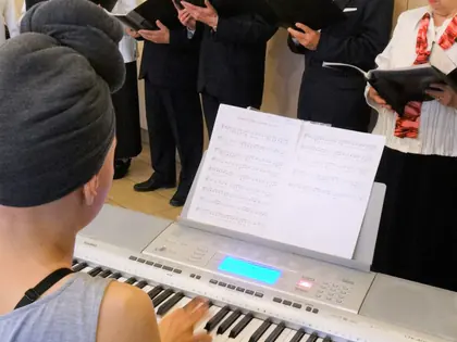 Chór w strojach koncertowych śpiewa przy akompaniamencie keyboardu